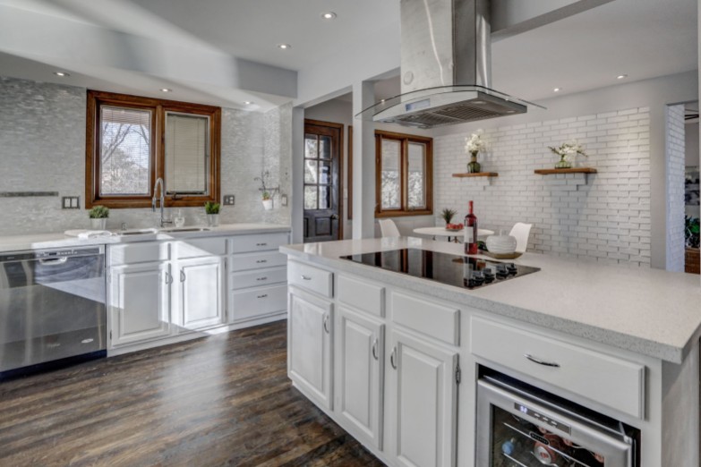 A white island with white cabinets and white tiled wall in this Colorado kitchen